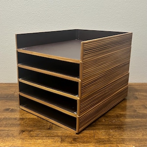 May include: A wooden desk organizer with five compartments. The organizer has a dark brown interior and a light brown, ridged exterior. The organizer is designed to hold papers, files, or other office supplies. The organizer is sitting on a wooden surface.