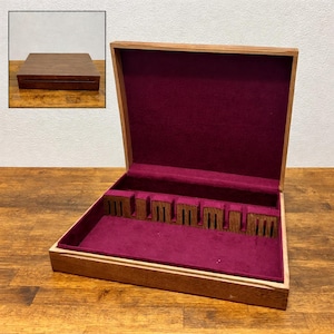 May include: Open wooden silverware box with a burgundy velvet interior. The box has slots for utensils and a hinged lid. The exterior is a light brown color, and the box is sitting on a wooden surface.