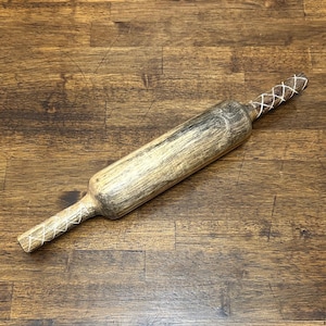 May include: A wooden rolling pin with a light brown and grey finish. The handles are decorated with white crisscross patterns. The rolling pin is designed for kitchen use and is placed on a wooden surface.