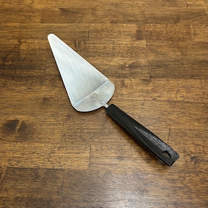 以下が含まれることがあります： 黒いハンドルが付いたステンレス製のパイサーバー。 サーバーは三角形の刃と、端に穴のある黒いテクスチャード加工のハンドルを備えています。 パイやケーキのカットとサーブ用に設計されています。