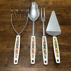 Puede incluir: Un juego de cuatro utensilios de cocina vintage con mangos color crema con un diseño colorido de frutas y verduras. El juego incluye un machacador de patatas, una cuchara de servir, un tenedor y una espátula para tartas. Los utensilios son de acero inoxidable.
