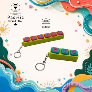 May include: Two lime green rectangular keychains with metal rings. One keychain features six pink square buttons with blue letters spelling KIERAN. The other keychain has three blue square buttons with pink letters spelling BUG. Both have a click mechanism.