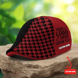 Könnte beinhalten: Eine flache Schiebermütze mit rot-schwarzem Hahnentrittmuster, einem einfarbig schwarzen Vorderteil und einem einfarbig roten Seitenteil. Die Seite zeigt schwarzen Text mit YOUR LOGO HERE, CUSTOM TEXT und CUSTOM NAME sowie einen roten Pfeil.