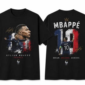 以下が含まれることがあります： 前面にキリアン・エムバペのグラフィック、KYLIAN MBAPPÉ FRANCEの文字、雄鶏のロゴがプリントされた黒いTシャツ。背面にはMBAPPÉの名前、背番号10、フランス国旗のデザイン、DREAM. BELIEVE. ACHIEVE.の文字が描かれています。
