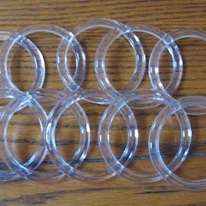 May include: A set of ten clear plastic rings, likely used for curtains or other home decor.