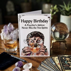 May include: A white greeting card featuring a colourful illustration of a person wearing a leopard print headscarf, holding a cocktail glass with two small ghosts emerging from it. The text reads Happy Birthday A Psychic's Advice: Never Mix the Two Spirits.