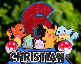 May include: A cake topper featuring a large red glittery number six, the name CHRISTIAN in black letters on a blue banner, and illustrations of Charmander, Bulbasaur, Jigglypuff, Pikachu, and Squirtle, flanked by two red and white Poké Balls.