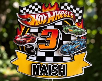 May include: A decorative cake topper featuring a checkered flag background, the Hot Wheels logo, a large orange number 3, and three toy cars in red, green, and blue. A yellow banner at the bottom displays the name NAISH in bold black letters.