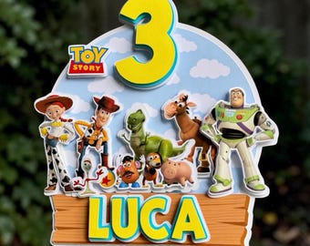 May include: A layered cake topper featuring the number 3 in yellow, the Toy Story logo, and various character cutouts including Woody, Buzz Lightyear, Jessie, Rex, and others. A wooden-style sign at the bottom displays the name LUCA in yellow.