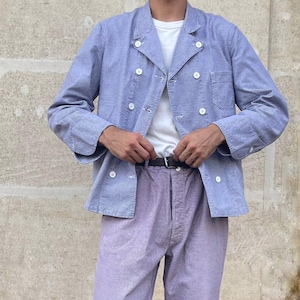 Puede incluir: Una chaqueta cruzada de rayas azules y blancas con botones blancos, una camiseta blanca lisa, pantalones de rayas de color violeta claro y mocasines de ante marrón. El conjunto incluye un cinturón de cuero marrón oscuro con hebilla plateada.