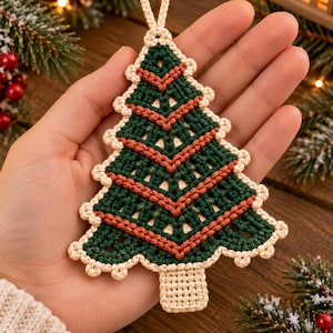 May include: A crochet Christmas tree ornament featuring dark green and rust-colored yarn in a chevron pattern. The tree is edged with cream-colored yarn in a scalloped stitch and includes a small cream-colored loop at the top for hanging.