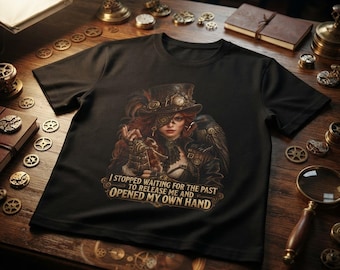 May include: A black t-shirt featuring a graphic of a person wearing a top hat and goggles with a raven on their shoulder. The text reads: I STOPPED WAITING FOR THE PAST TO RELEASE ME AND OPENED MY OWN HAND. The design includes intricate gear details.
