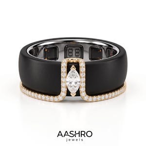 May include: A matte black ring featuring a gold-toned band inlay adorned with small round diamonds and a central marquise-cut diamond. The interior of the ring displays electronic sensor components. The text AASHRO jewels is printed below.