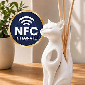 Op de afbeelding: Een witte, matte katvormige houder voor een geurstokjesdiffuser met een ronde uitsparing in het lichaam en een glazen buisje met drie houten stokjes. Een blauw en goud embleem met de tekst NFC INTEGRATO is over de afbeelding geplaatst.