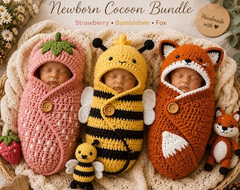 May include: A 3-in-1 newborn cocoon bundle featuring three crocheted swaddles: a pink strawberry with green leaves, a yellow and black bumblebee with white wings, and an orange fox with white accents. Each includes a wooden button closure.