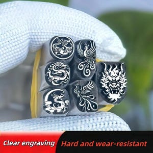 May include: A set of five silver-toned metal stamps featuring intricate engravings of dragons and phoenixes. The stamps are bundled together with a yellow rubber band. Text at the bottom reads: Clear engraving, Hard and wear-resistant.