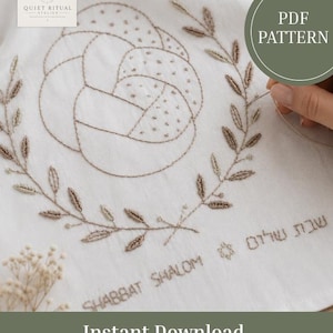 May include: A white fabric featuring brown embroidery of a braided challah bread surrounded by a leafy wreath. Below the wreath, the text reads "SHABBAT SHALOM" in English and Hebrew, accompanied by a small Star of David symbol. The image includes a PDF PATTERN label.