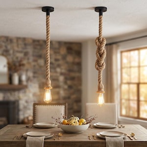 Pode incluir: Duas luminárias pendentes com cordas de juta de cor natural, suspensas por suportes circulares pretos no teto. Cada corda termina num bocal com uma lâmpada de estilo Edison acesa. Uma das cordas apresenta um nó decorativo.