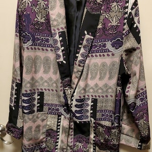 May include: A purple, black, and beige patterned blazer with a shawl collar. The blazer has a Kensington label.