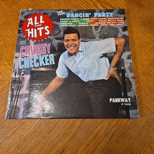 May include: Vintage vinyl record album cover for "All The Hits" by Chubby Checker. The cover features a smiling man in a striped shirt. Text includes "Dancin' Party" and other song titles. The Parkway label is visible.