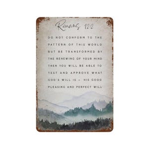 May include: A rectangular metal sign with a distressed rust-coloured border featuring a watercolour landscape of mountains and trees at the bottom. The text reads: Romans 12:2 DO NOT CONFORM TO THE PATTERN OF THIS WORLD BUT BE TRANSFORMED BY THE RENEWING OF YOUR MIND THEN YOU WILL BE ABLE TO TEST AND APPROVE WHAT GOD'S WILL IS - HIS GOOD PLEASING AND PERFECT WILL.