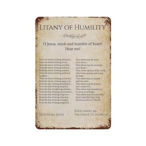 Op de afbeelding: Een rechthoekig metalen bord met een verweerde, beige achtergrond en donkerbruine roestige randen. Het bevat de tekst Litany of Humility, een gebed, en de zin Deliver me, Jesus! gedrukt in een duidelijk, donker schreeflettertype.