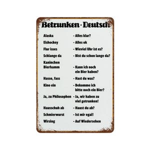 May include: A rectangular metal sign with a white background and a distressed, rusted brown border. The sign features the black text 'Betrunken-Deutsch' at the top, followed by a two-column list of German phrases and their humorous interpretations.