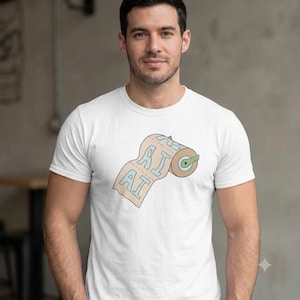 Può includere: Una t-shirt bianca a maniche corte con un'illustrazione grafica di un rotolo di carta igienica nei toni del beige e dell'azzurro. Il rotolo di carta igienica presenta le lettere AI stampate in un carattere blu grassetto sui fogli, con un nucleo verde.