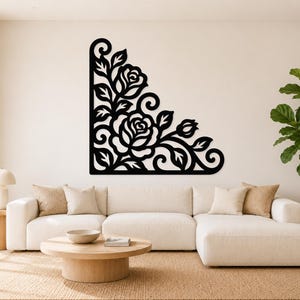 May include: A black wall-mounted corner decoration featuring a laser-cut design of two blooming roses, swirling vines, and pointed leaves. The piece is shaped as a right-angled corner accent with a flat, solid black finish and intricate cutouts.