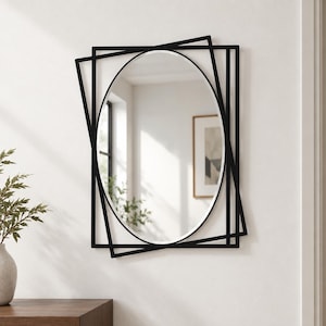 May include: A wall mirror featuring a central oval glass pane encased within a black metal frame composed of multiple overlapping rectangular outlines. The geometric frame creates a layered effect around the smooth, reflective oval surface.