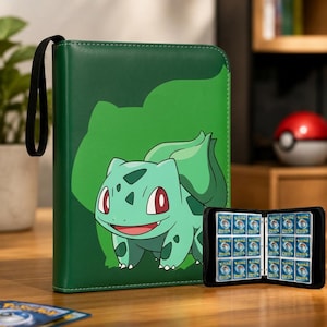 Op de afbeelding: Een groene verzamelkaartenmap met een afbeelding van het personage Bulbasaur op de voorkant. De map heeft een zwarte polsband en is opengeklapt weergegeven, met meerdere doorzichtige plastic hoesjes waarin kleine rechthoekige spelkaarten zitten.