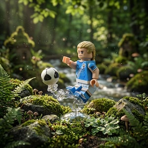 May include: A blonde minifigure wearing a light blue Manchester City soccer jersey with the Etihad Airways logo and matching shorts, balancing a black and white soccer ball on one foot while mounted on a clear plastic display stand.