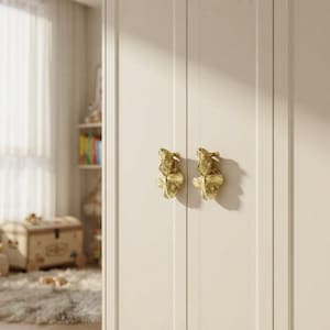 May include: Two gold-colored metal cabinet knobs shaped like goldfish with detailed scales and flowing fins. The knobs are mounted on a light-colored, vertical-paneled cabinet door, featuring a metallic finish and a realistic fish design.