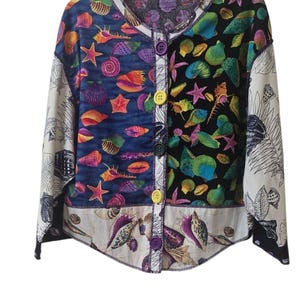 May include: A long-sleeve button-down shirt featuring a patchwork design of colourful seashells and starfish on blue and black backgrounds, with white sleeves printed with black shell outlines and five large, multi-coloured plastic buttons.
