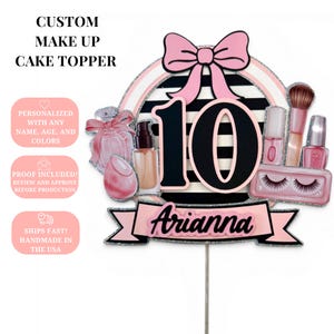 May include: A custom cake topper featuring the number 10 in black with pink outlines, centered on a circular background with black and white horizontal stripes. It is decorated with a pink bow, makeup items, and a banner displaying the name Arianna.