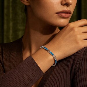 May include: A silver-toned chain bracelet featuring rectangular links with inlaid bright blue, textured stone accents. The bracelet is constructed with alternating metal links and blue rectangular segments, creating a continuous, flexible band design.