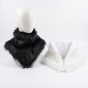 May include: A black faux fur neck warmer displayed on a mannequin head and a separate white faux fur neck warmer with a front zipper closure. Both accessories feature long, soft synthetic fibers and are designed to sit around the neck area.