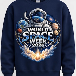Pode incluir: Uma camisola azul-marinho de gola redonda com um gráfico de um astronauta, planetas e o lançamento de um foguetão. O texto diz World Space Week 2026. O design inclui uma vista detalhada da Terra refletida na viseira do capacete.