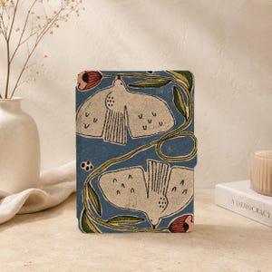 Può includere: Una custodia rettangolare per e-reader con sfondo blu e un motivo ripetuto di due uccelli color crema con ali spiegate, steli verdi e piccoli boccioli di fiori rossi. Il design presenta un aspetto testurizzato sulla copertina.