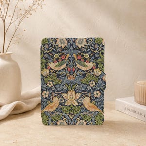 May include: A rectangular tablet case featuring a dark blue background with a repeating pattern of light-coloured birds, green foliage, and small red strawberries. The design includes intricate floral elements and symmetrical botanical motifs.