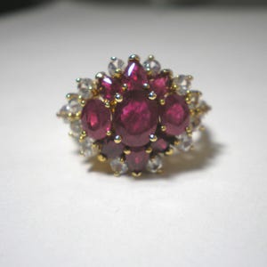 May include: A gold ring with a cluster of red rubies and white diamonds. The ring is set in a floral design.