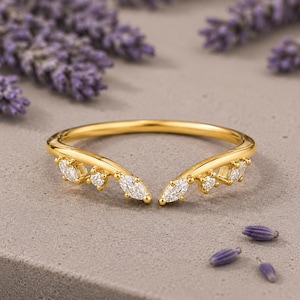 Peut inclure: Une bague ouverte en or avec un design en forme de V ornée de pierres claires taillées en marquise et en rond. L'anneau est en or poli et les pierres sont serties le long des deux extrémités de la bague ouverte, créant un aspect symétrique.