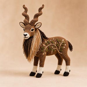 May include: A brown crochet markhor figurine featuring long, spiraled horns, a thick mane of tan and dark brown yarn, and white lower legs with dark brown hooves. The body is decorated with an embroidered green leaf and white flower vine pattern.