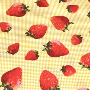 May include: A yellow and white checkered fabric with a repeating pattern of red strawberries. The strawberries are scattered randomly across the fabric.