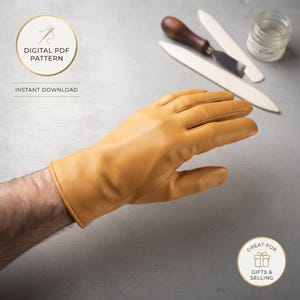 May include: A mustard yellow leather glove with visible stitching details. The image includes text that reads DIGITAL PDF PATTERN INSTANT DOWNLOAD and GREAT FOR GIFTS & SELLING, alongside a wooden handled tool and a small glass jar.