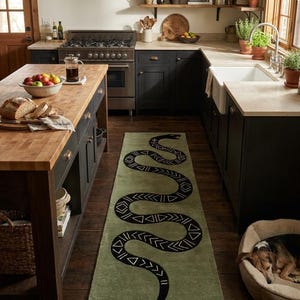 Peut inclure: Un tapis de couloir rectangulaire vert olive orné d'un grand serpent noir sinueux. Le corps du serpent est décoré de motifs géométriques blancs, notamment des triangles et des chevrons, qui parcourent toute sa longueur sur le sol.