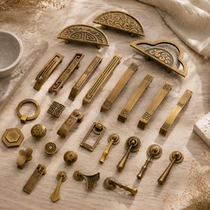 May include: A collection of antique brass cabinet hardware including various drawer pulls, knobs, and handles. The set features semi-circular, rectangular, and circular shapes with intricate geometric, floral, and linear engraved patterns.