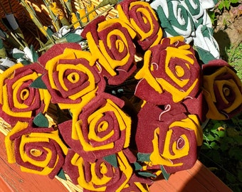 Op de afbeelding: Een boeket van viltrozen in tinten rood, geel en groen. De rozen zijn in een mandje gerangschikt en zijn met een lint aan elkaar gebonden.