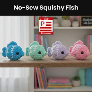 Puede incluir: Cuatro pequeños juguetes de pez de peluche tejidos a ganchillo, dispuestos en fila. Cada pez presenta un cuerpo de hilo suave y texturizado con un patrón de rayas blancas, ojos de botón negro y aletas pequeñas. Los colores son azul, verde menta, morado claro y rosa claro.