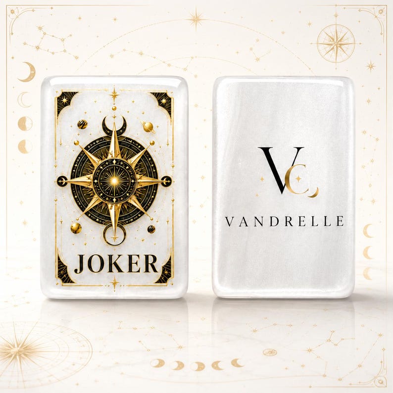 Puede incluir: Dos cartas de juego rectangulares blancas con esquinas redondeadas. La carta izquierda presenta un dise&ntilde;o de br&uacute;jula en oro y negro con la palabra JOKER. La carta derecha muestra un logotipo negro con las letras VC y el nombre VANDRELLE.